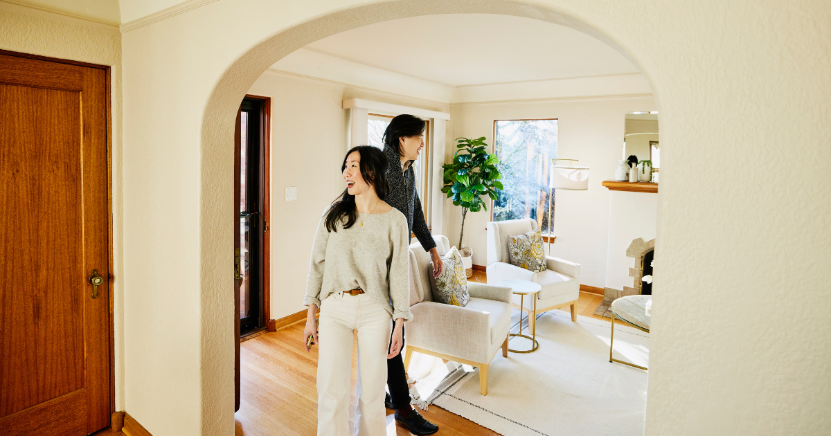 Smiling couple touring a home during a showing, representing today’s slower housing market where buyers have more time and options.