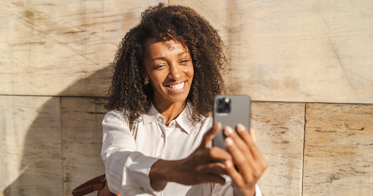 Smiling professional sitting outside recording a video of herself delivering a market update to her clients.