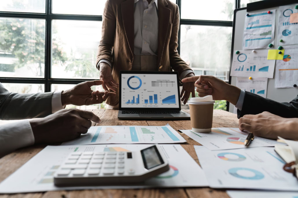 Business people meeting using laptop computer, calculator, stock market chart paper for analysis planning to improve quality next month. Conference discussion corporate concept